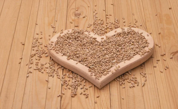 Kalp şeklinde bir tahta tabakta buğday taneleri. Yaklaş..