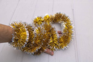 Yakından çekilen altın noel süslemesi elimize sarılı.