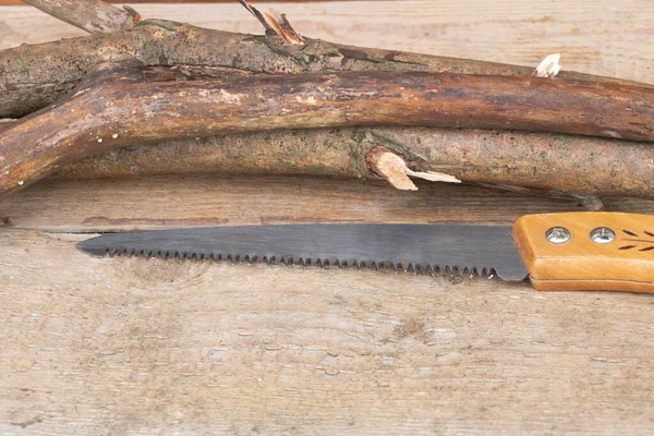 Una sierra pequeña para cortar ramas delgadas - Fondo de madera — Foto de Stock