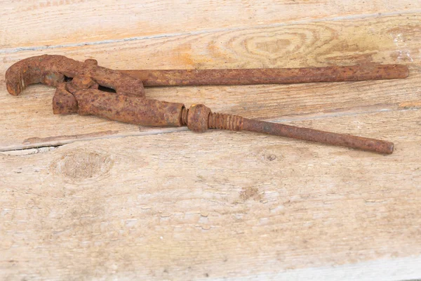 Uma velha chave de ferro enferrujado ajustável no fundo de madeira — Fotografia de Stock