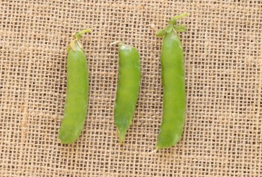 Kırsal bir kumaş zemin üzerinde yeşil bezelyelerin yakın plan çekimi..