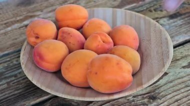 Bir adam tabaktan taze kayısı meyvesi alır.