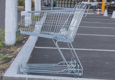 Marketin otoparkında içi plastik torbalarla dolu boş bir alışveriş arabası..