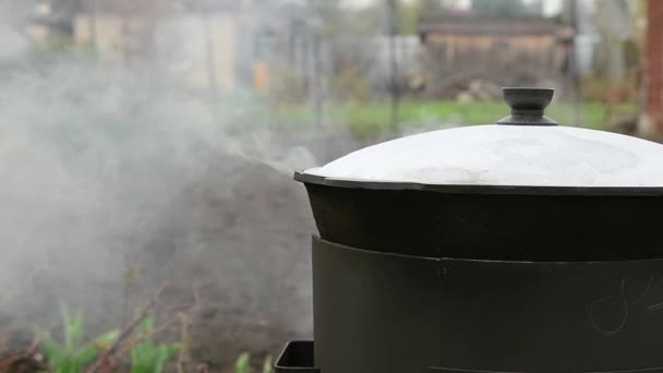 フードは中庭の外にある釜で調理されます 沸騰した水蒸気 スローモーション 男は鍋の蓋を開ける 二つのビデオ — ストック動画