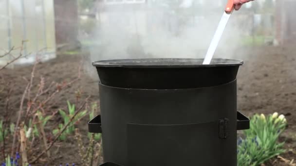 フードは中庭の外にある釜で調理されます 少女は柄杓で鍋にかき混ぜている 熱湯蒸気を沸かす — ストック動画