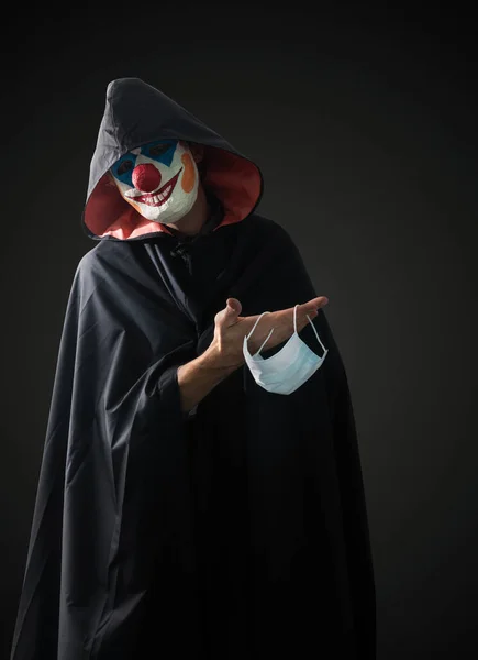 Clown Een Donkere Achtergrond Met Een Medisch Masker Zijn Hand — Stockfoto