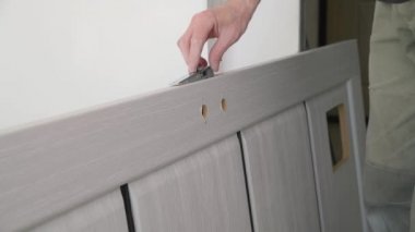 Tahta kapıya metal bir kilit takmak. Lastik bir çekiçle çekiç sallamak. Onarım işi.