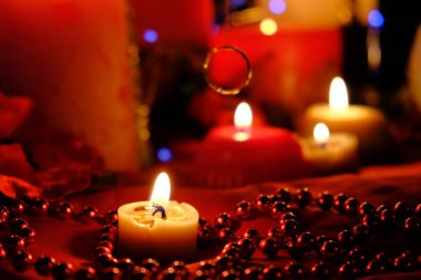Fortune-telling on candles, fire and a ring, Russian fortune-telling for love at Christmas. Burning red candles, heart shaped candles, ruby beads on the table.Occult concept. February 14 decoration