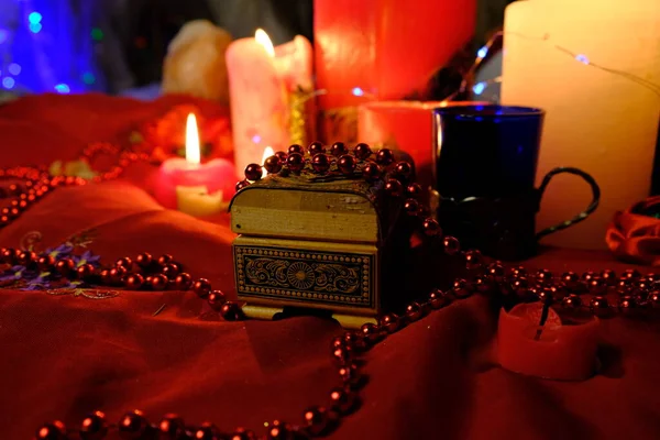 Fortune-telling on candles, fire and a ring, Russian fortune-telling for love at Christmas. Burning red candles, heart shaped candles, ruby beads on the table.Occult concept. February 14 decoration