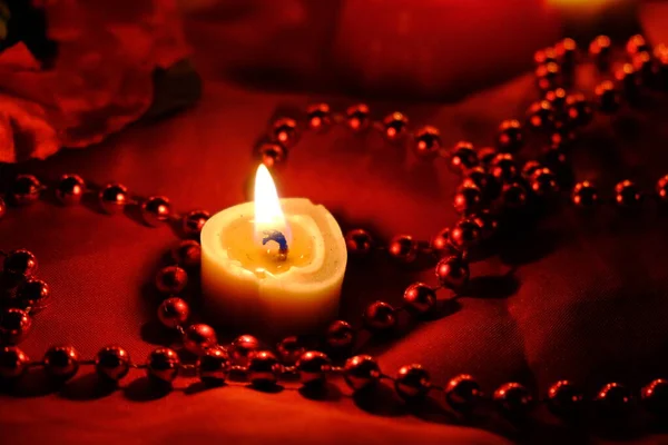 Fortune-telling on candles, fire and a ring, Russian fortune-telling for love at Christmas. Burning red candles, heart shaped candles, ruby beads on the table.Occult concept. February 14 decoration