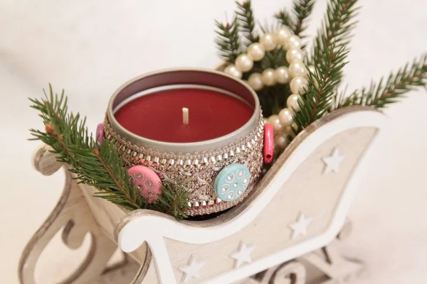 一支红色的蜡烛 插在装饰雪橇上 一个心地善良的天使 圣诞树枝 白色珠子 用石头把蜡烛在铁盒子里打蜡 侧视的角度 有选择的重点 — 图库照片
