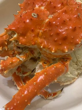 Saha koşullarında pişmiş yengeç. Sakhalin yengeci, dokunaçlar ve parçaları bir tabakta. Deniz ürünlerine yakın çekim, leziz bir yemek..