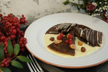 Viburnum çileğiyle süslenmiş beyaz ve siyah çikolatadan yapılmış gözlemeler. Çocuklar için tatlı krepler. Shrovetide, Slav bayramları, geleneksel un yemekleri.