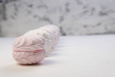 Beyaz arka planda ambalajsız şekerlemeler. Yan görünüş. Zephyr pembe ve beyaz. Protein tatlılığı. Hava tatlısı.