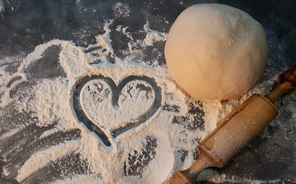 Testteki yuvarlak formun yarı bitmiş bir ürünü. Un kalpli. Tahta kaya. Un ürünü. Çok sayıda ürün için el kalıbı. Konsept: ev yemeği, mayasız hamur..