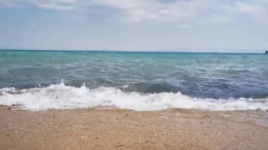 Kumsalda dalgaları yenmek. Zümrüt renginde güzel bir su manzarası, hareketli rüzgarlı deniz. Kıyıdan okyanusa manzara, tüm aile için dinlenme ve dinlenme yeri.