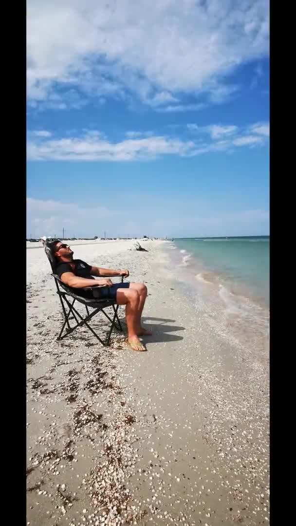 선수가 해변의 해변에 휴대용 의자에 아조프해를 바라본다 소리에 휴식을 취하라 — 비디오