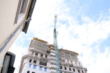 Yüksek bir binanın inşaatı sırasında vinç inşaatı. Ağır bir yük taşıyorum. Kule vinçleri bir ev inşa ediyor. Beton bina yapım aşamasında. İnşaat alanı