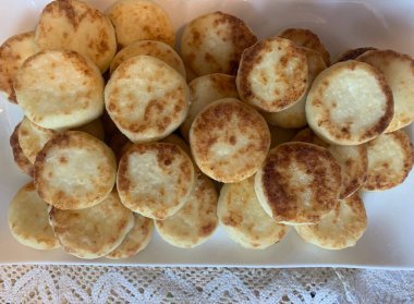 Cottage cheese and syrniki in large quantities. Delicious breakfast, golden cheesecakes served with powder. Caloric food, healthy ingredients