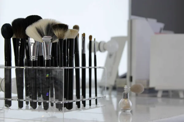 Sets of makeup brushes and cosmetics on a bright workplace of a make-up artist.Brushes for applying eye shadow and foundation. Concept: makeup cabinet, stylist and makeup artist tools