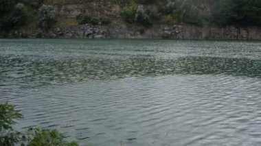 Sunny day at an artificial quarry with emerald water. A beautiful location for a picnic and outdoor recreation, a stone shore, a deep quarry, a place for fishing