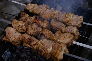 Bir adam ateşte et pişirir. Elleri yakın çekim ve şiş kebap. Izgarada domuz boynu pişirmek. Kızarmış havuç. Yağlı yiyecekler, BDT ülkelerinin şenlikli yemekleri. 1 Mayıs, İşçi Bayramı. Vejetaryen yemeği değil.