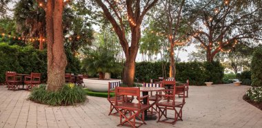 Gün batımında arka planda fıskiyelerle birlikte saklı bir bahçenin üzerinde parlayan ışıklar..