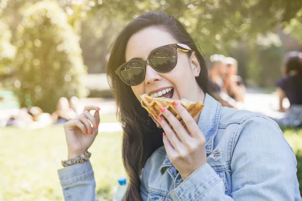 young latina woman smiles and eats a waffle at an outdoor summer concert or music festival