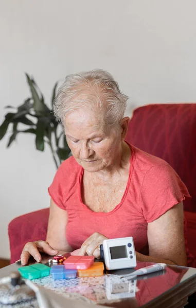 elderly woman checking her medication, sphygmomanometer and oximeter at home