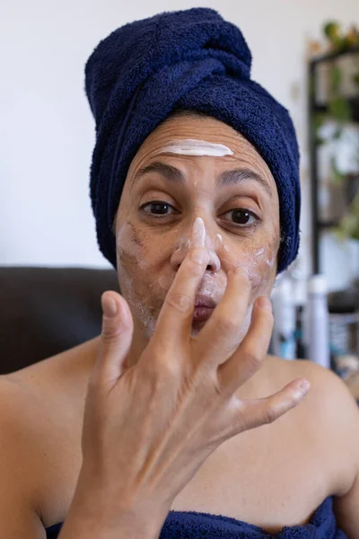 mature middle eastern woman at home applying treatment cream after a deep chemical peel with acid to remove skin blemishes.