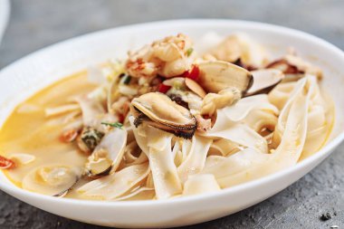 Bir tabak lezzetli sotelenmiş baharatlı deniz mahsulü eriştesi, yakın çekim manzaralı.