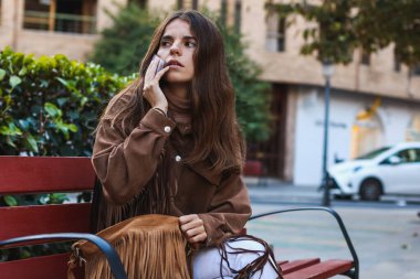 Kız bankta oturdu ve telefonuyla aradı.