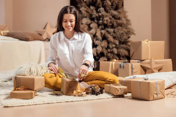 Молодая женщина упаковывает рождественские подарки на праздники — стоковое фото