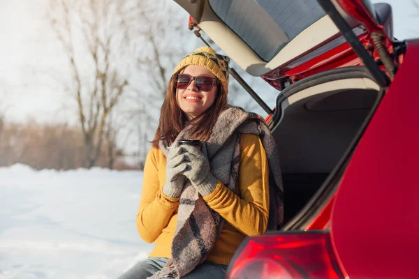 Woman with coffee paper car has winter car picnic