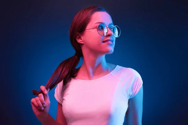 Neón primer plano retrato de mujer joven gafas de sol redondas y vestido blanco sobre fondo azul oscuro — Foto de Stock