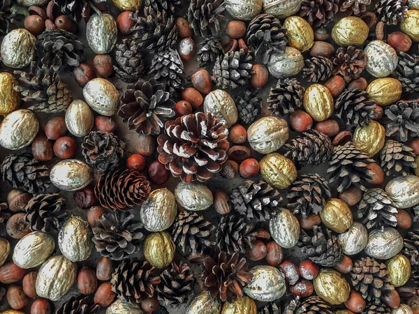 Textura de fondo de ambiente otoñal formada por conos de pino, nueces doradas y plateadas y colocadas sobre una mesa —  Fotos de Stock