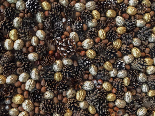 Textura de fondo de ambiente otoñal formada por conos de pino, nueces doradas y plateadas y colocadas sobre una mesa —  Fotos de Stock