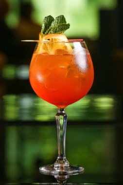 Yeşil arka planda alkollü aperol kokteyli.