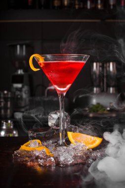 Siyah zemin üzerinde meyve ve buz olan kokteyl içeceği.