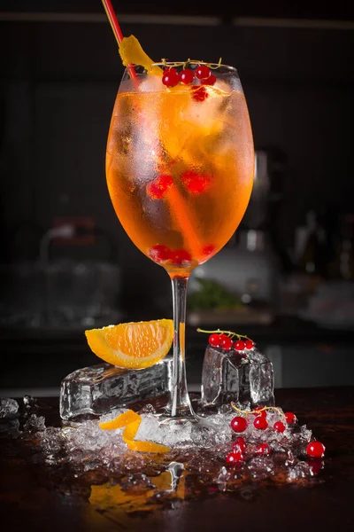 Spritz cocktail drink with orange and ice cubes on black background