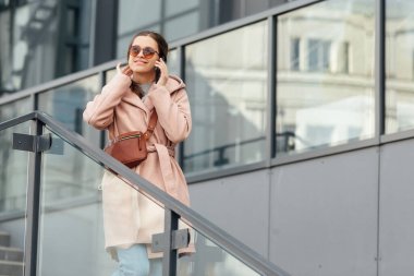 Pembe elbiseli bir kadın gri şehir arka planında zeki biriyle konuşuyor.