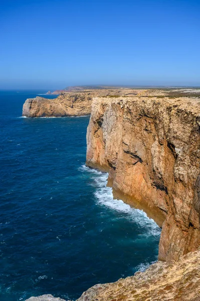 Portekiz 'deki Algarve' de yüksek engebeli kayalıkları olan güçlü dalgaları olan bir sahil..