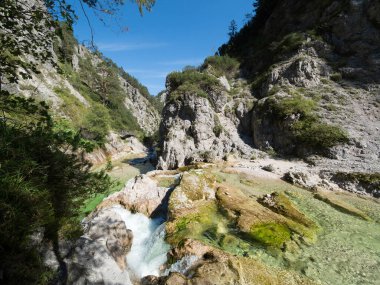 Engebeli kaya duvarları olan dar bir vadide berrak bir dağ nehri..