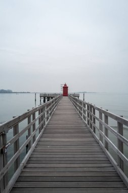 Uzun bir iskelede küçük kırmızı bir deniz feneri..