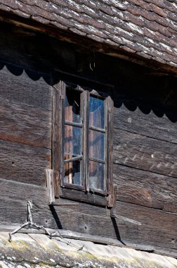 Broken window at an old uninhabited wooden house.