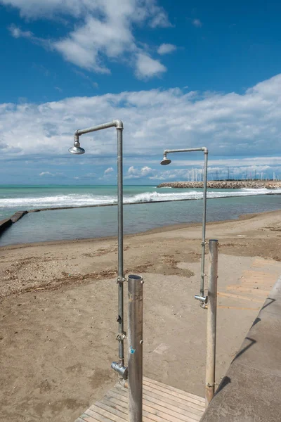 Issız bir kumsalda banyo yapmayı bekleyen iki yaşlı duş var..