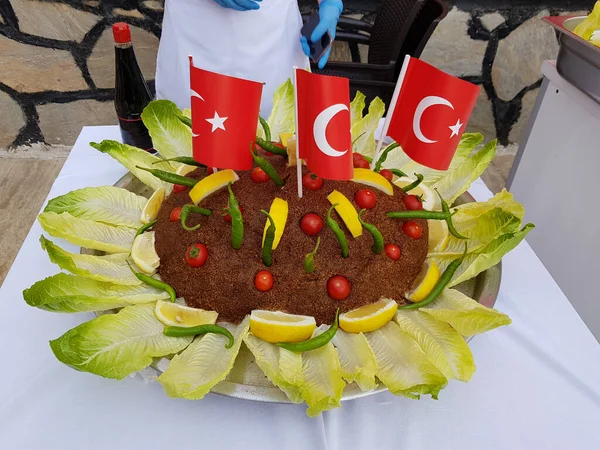 Turkish national food Cig kofte garnished with lettuce, lemon, tomato, hot peppers and Turkish flags. Turkish national food