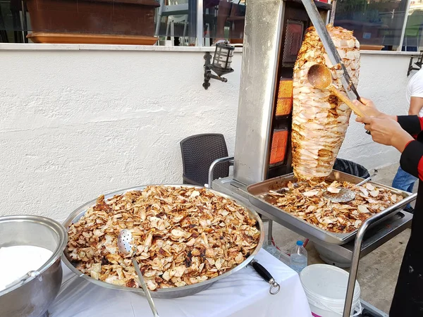 A cook cuts chicken meat on a skewer to cook shawarma. Traditional Turkish food Doner Kebab. Fast street food