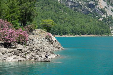 Manavgat, Türkiye - Haziran 05, 2019: Bir balıkçı Yeşil Kanyon 'daki dağ kayalıkları arasında bir gölde balık yakalıyor