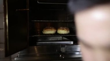 Şef hamburgerleri fırında pişirir.